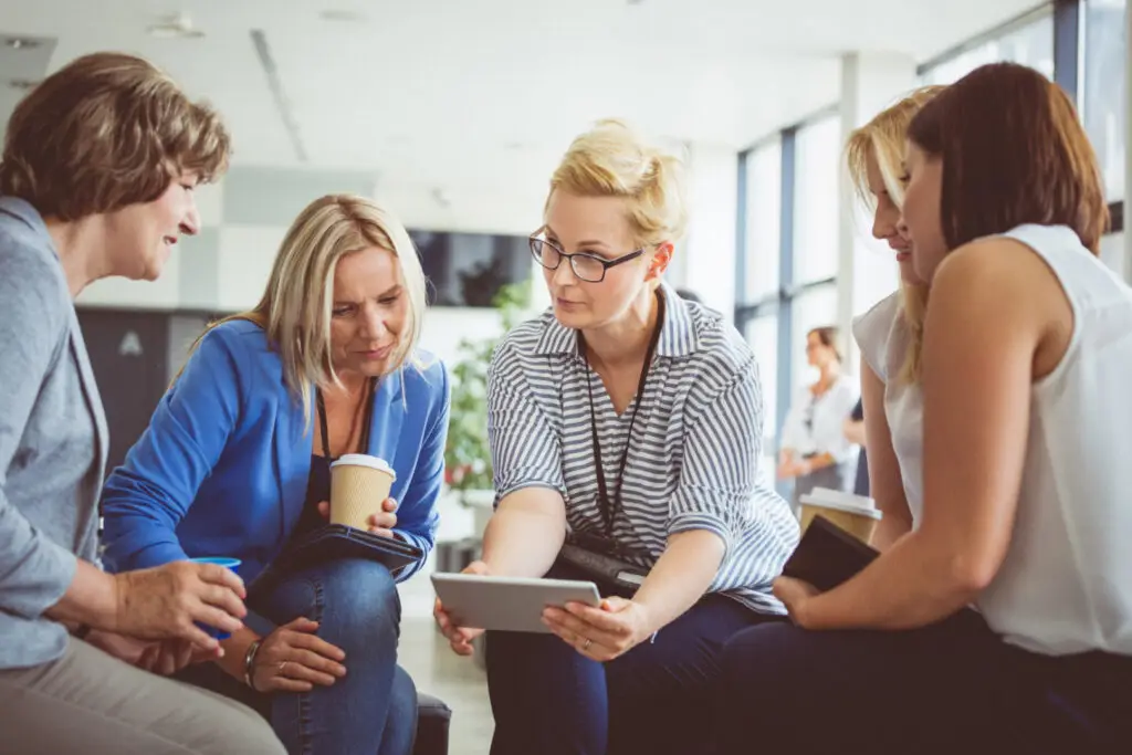 Gruppengespräch mit fünf Frauen zum Thema Entwicklungs- und Sozialcoaching mit AVGS-Gutschein. Sie unterhalten sich.