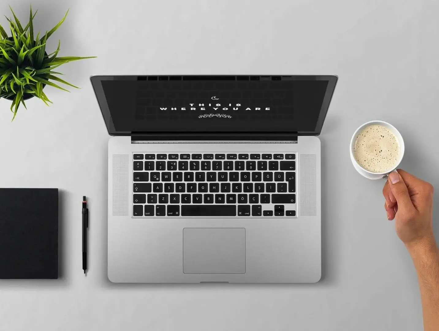 Ein Laptop mit einem Spruch auf dem Bildschirm 'This is where you are' und jemand mit einer Tasse Kaffe in Vorbereitung auf das Coaching.