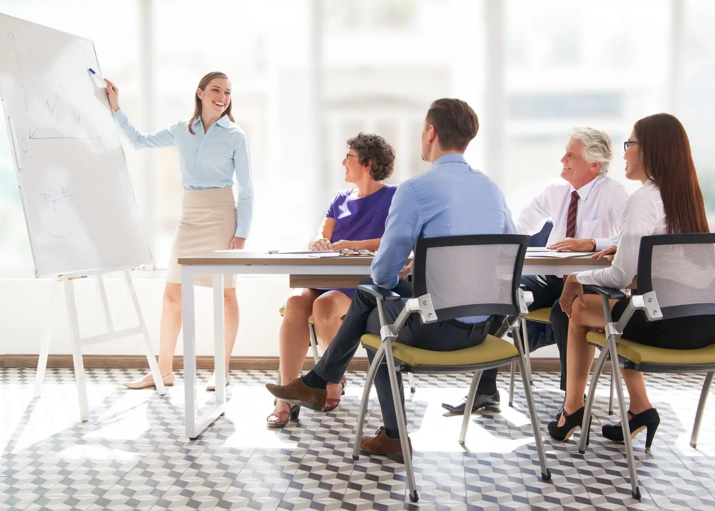 Business-Coaching-Sitzung in Dresden, bei der eine junge Trainerin AVGS-geförderte Methoden an einer Flipchart präsentiert, umstrahlt von aufmerksamen Teilnehmern, die berufliche Weiterbildung durch AVGS-Maßnahmen anstreben.